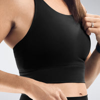 Person wearing a black sports bra against a neutral background