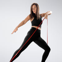 Woman exercising with a resistance band on a plain background
