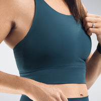 Person wearing a teal sports bra against a neutral background